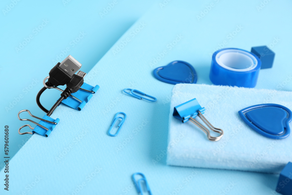 Set of stationery and USB cable on color background, closeup