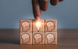 brainstorming creative idea and innovation. Hand putting over wooden cube block with light bulb icon on many people together having an idea symbolized by icons on cubes.