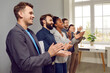© Studio Romantic - Multinational people working in same company applaud after performance or refresher training and participate in team building activities stand in office along wall. Corporate culture concept