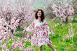 © dmitriisimakov - a woman dancing in a garden of blooming pink trees nature park spring