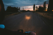 Cropped Image Of Man Driving Motorcycle On Country Road During Sunset