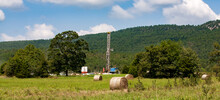 Drilling Rig On Grassy Field Against Mountain At Arkoma Basin During Sunny Day