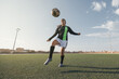 © Cavan Images - Young female soccer player kicking ball in a stadium.