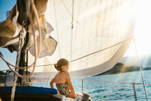 Girl On Sailboat With Sun Rays On Lake In Summer Sunshine