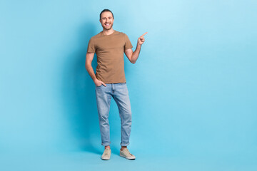 Canvas Print - Full length photo of cheerful positive guy dressed beige t-shirt pointing finger empty space isolated blue color background