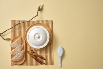 Canvas Print - Top view of a white bowl decorated with a dish of edible bird’s nest, ginseng (Panax ginseng) and a branch. Minimalist background. Bird's nest with ginseng has many benefits to brain, health and skin