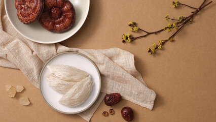 Wall Mural - Salanganes nest raw on round dishes, red reishi mushroom, jujube on brown background. There are ingredients for distilling premium bird's nest. Top view, flat lay.