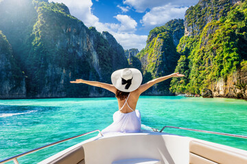 happy tourist woman in white summer dress relaxing on boat at the beautiful phi phi islands, tourism