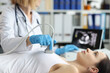 © H_Ko - Doctor holds ultrasound probe on chest of patient in clinic closeup