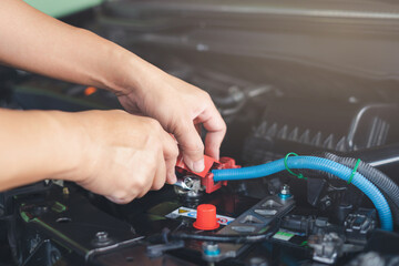 Wall Mural - Close up hand service man use wrench lock bolt of Battery terminal after change new car battery in engine room , service concept and car mainternance