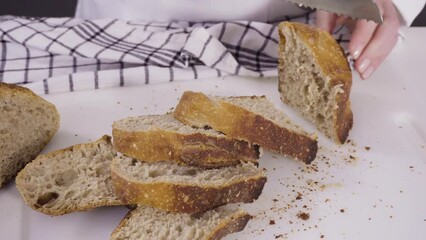 Sticker - Slicing freshly baked sourdough wheat bread on a white cutting board.