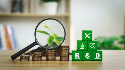 The abbreviations R and D stand for research and development.  The initials rested on a green wooden block with a coin, a magnifying glass and a sapling.