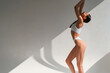 © standret - View from the side. Young caucasian woman with slim body shape is indoors in the studio