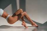 On the legs and hands. Close up view. Young caucasian woman with slim body shape is indoors in the studio