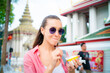 © themorningglory - Woman enjoy eat street food ice cream travel in buddha temple