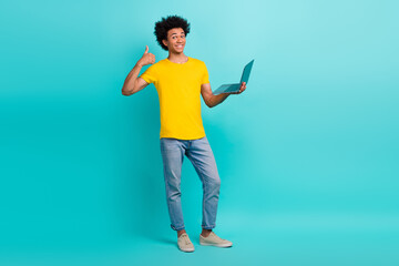 Full length photo of handsome guy hold netbook demonstrate thumb up isolated on teal color background