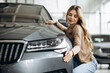 Young woman hugging a car in a car showroom