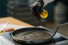A Chef Pours Oil Into A Hot Pan In A Professional Kitchen Cooking In A Restaurant