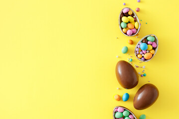 Wall Mural - Easter sweets idea. Top view photo of chocolate eggs with сolorful dragees and sprinkles on isolated yellow background with empty space. Easter concept
