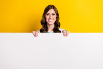 Poster - Photo of lovely satisfied woman with curly hairstyle wear striped shirt hold billboard presenting sale isolated on yellow color background