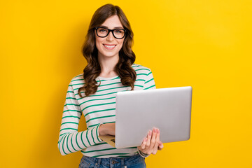 Photo of brown curly hair young professional programmer positive woman hold netbook creative project seo manager isolated on yellow color background