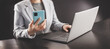 © candy1812 - Woman in the office holding in her hands mobile phone and typing on the laptop.