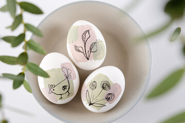 Wall Mural - Bowl with modern creative trendy  hand painted easter egg in spring flowers on white background.  Homemade tradition Easter ideas. Greeting card