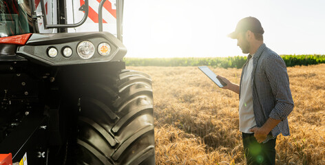 Sticker - Farmer with digital tablet stands next to combine harvester. Smart farming concept.	