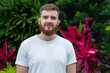 © Евгений Шемякин - Portrait of happy young bearded man with beard breathing deep, inhale fresh air on natural background, green wall with leaves, flower in tropical country in garden. Eco, ecological concept.