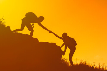 Hikers helping each other climb up a mountain working as a teem 