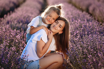 Wall Mural - Happy family in purple lavender field. young beautiful mother and child Girl enjoy walking blooming meadow on summer day. Mom having fun with pretty daughter in nature on sunset. mothers day