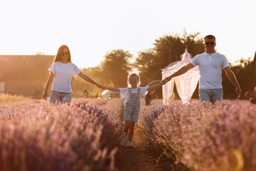 Wall Mural - happy family day. young father, mother and child daughter are having fun together in the lavender field and looking at each other. happy couple with kid enjoy summer holiday vacation. family look