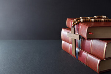 Wall Mural - Religious books and cross isolated on black table and background