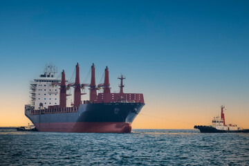 large carrier ship floating  afternoon in sea, tugboat dragging container ship, blue sky evening background and sea front,