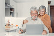 Old age and modern tech. Retired family couple sit at kitchen table use laptop watch photo video read latest news online. Aged husband share discuss interesting information on website with senior wife