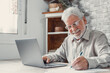 © Daniel - Aged remote worker. Concentrated senior male in glasses work on laptop from home office read email electronic document. Old age man employee freelancer sit at kitchen table by pc typing report online.