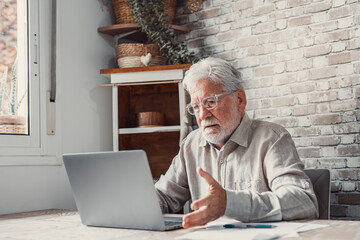 Annoyed worried aged man pensioner sit by laptop unable to make utility bill loan payment online has question how to use app need help. Stressed old grandpa confused with unexpected debt on pc screen.