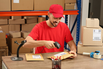 Canvas Print - Post office worker with scanner reading parcel barcode at counter indoors