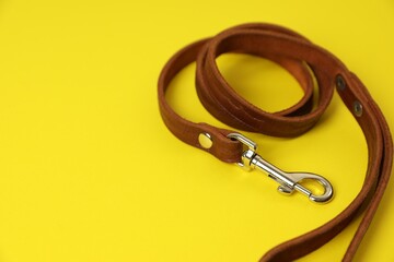 Wall Mural - Brown leather dog leash on yellow background, closeup. Space for text