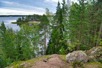 Wall Mural - Huge boulders stones covered with moss and pine forest near beatiful fresh blue lake, Park Mon Repos, Vyborg, Russia