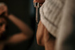 © La Famiglia - Rear view of a woman is using anti aging serum treatment on her face at home in the bathroom.
