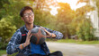 Portrait of asian male teenager in plaid shirt holding old and training basketball in hand with blurred park background, sunlight edited.