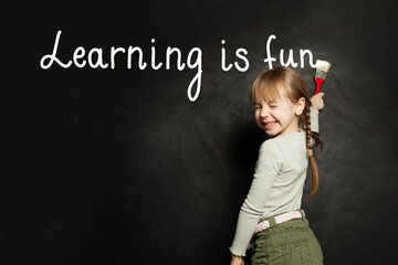 Wall Mural - School child girl writing on the blackboard with chalk. Learning is fun, study, education concept