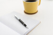 © Cavan Images - Close-up of book and pen by coffee cup on white background