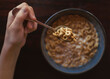 © Cavan Images - Cropped hand of boy holding breakfast with spoon over bowl on table at home