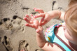 © Cavan Images - High angle view of girl removing sand from her wet hand at beach during summer