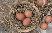 Overhead View Of Brown Eggs With Hay In Wooden Container On Table At Farm