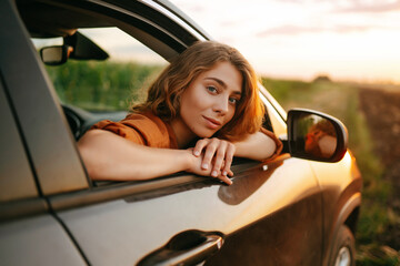 Wall Mural - Happy woman outstretches her arms while sticking out the car window. Lifestyle, travel, tourism, nature, active life.