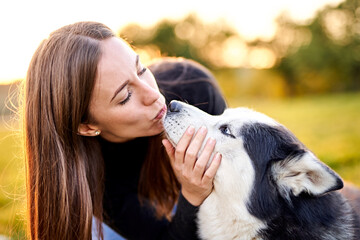 Siberian husky playing in grass outdoors with the owner girl together - Human and dog friendship and loyalty concept outside on a countryside field