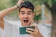 scared or surprised young man or student looking at mobile phone